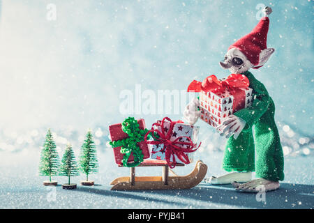 Cute Cheerful Santas Helper Elf Loading Cadeaux de Noël sur Santas Sleigh. Scène de Noël au pôle Nord. Santas Atelier. Elf au travail. Banque D'Images