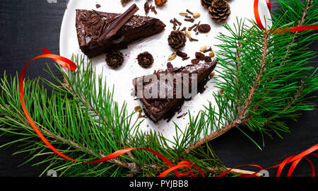 Gâteau bundt d'épice pour Noël et des décorations, des oeillets, des bâtons de cannelle, sur fond noir, le chocolat noir gâteau au chocolat Banque D'Images