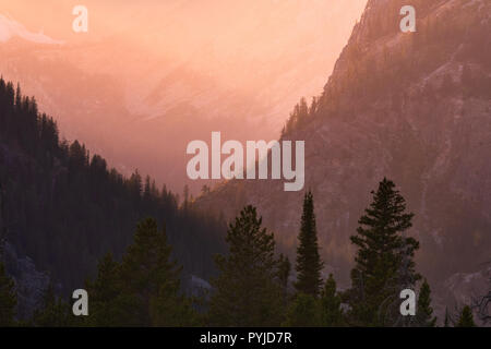 La lumière du soleil de fin de soirée se lave sur la base de l'établissement Grand Tetons embrasé le lointain de l'air brumeux entourant la vallée de basse altitude composé d'un rock Banque D'Images