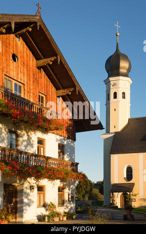 Clocher de l'église de l'église de pèlerinage baroque Wilparting et façade d'une taverne de fleurs de géraniums sur les balcons en bois, Bavière, Allemagne Banque D'Images