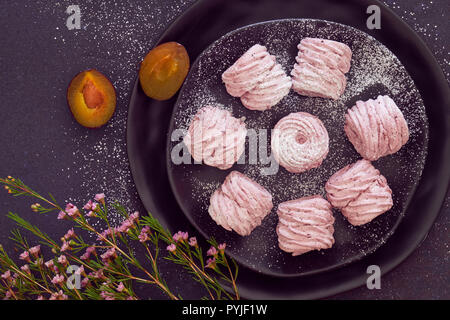 Mise à plat d'une plaque de guimauves (zephyr, meringue) fait avec les prunes noir sur noir Banque D'Images