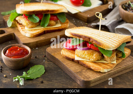 Sandwich avec tomates, fromage, Nuggets de Poulet croustillant et la Roquette. Des délicieux club sandwich au poulet sur une table en bois. Le fast food. Banque D'Images