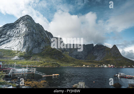 Célèbre attraction touristique de Reine dans les Lofoten avec vue sur Reinebringen, la Norvège avec red rorbu maisons, nuages, jour de pluie avec pont et une herbe Banque D'Images