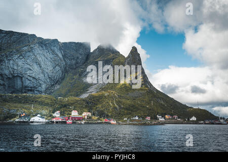 Célèbre attraction touristique de Reine dans les Lofoten avec vue sur Reinebringen, la Norvège avec red rorbu maisons, nuages, jour de pluie avec pont et une herbe Banque D'Images