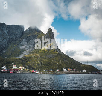 Célèbre attraction touristique de Reine dans les Lofoten avec vue sur Reinebringen, la Norvège avec red rorbu maisons, nuages, jour de pluie avec pont et une herbe Banque D'Images