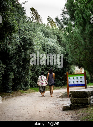 Vue arrière d'un couple hippie en passant devant un panneau dans un parc. Banque D'Images
