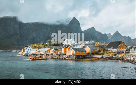 Maisons de rorbu jaune Sakrisoy village de pêcheurs sur un jour nuageux avec des montagnes en arrière-plan. Les îles Lofoten, Norvège. Photo prise en Norvège. Banque D'Images