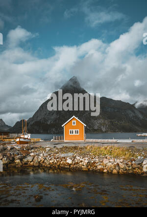 Maisons de rorbu jaune Sakrisoy village de pêcheurs sur un jour nuageux avec des montagnes en arrière-plan. Les îles Lofoten, Norvège. Photo prise en Norvège. Banque D'Images
