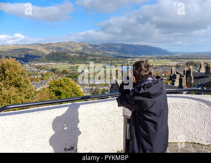 Garçon à l'aide de télescope sur le château de Stirling pour admirer la vue de la Wallace Monument à distance , Stirlingshire, Ecosse, Royaume-Uni. Banque D'Images