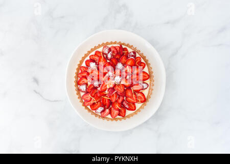 Tarte aux fraises faite maison à la crème de citron et décoré avec des zestes de citron sur un plat à gâteau blanc et blanc en arrière-plan.. Vue d'en haut. Banque D'Images