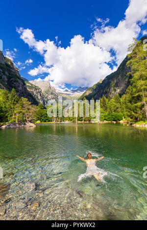 Un garçon nage dans un lac alpin. Val di Mello(Mello Valley), Valmasino, Valtellina, Lombardie, Italie, Europe. Banque D'Images