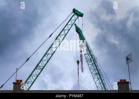 Bras de grue ou estacades ou crane grues silhouetté contre un ciel orageux gris Banque D'Images