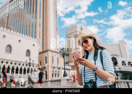 Belle Dame de discuter avec un ami sur un smartphone et debout sur le pont en journée ensoleillée. Femme à l'aide de guide en ligne Tourisme Sortir à partir de la livre Banque D'Images