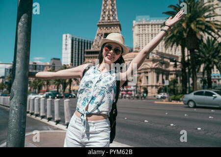 Carefree girl touriste à las vegas destination le port de lunettes de soleil et chapeau de paille. Backpacker joyeuse raising hand sur journée ensoleillée alors que d' voyage en Americ Banque D'Images