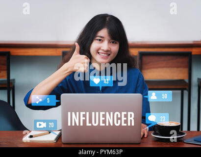 Asian woman influenceur Thumbs up et sourire à l'aide d'un ordinateur portable avec une tasse à café dans un café restaurant,femme blogger travaillant à l'extérieur social,digital lifestyle conc Banque D'Images