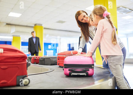 Mère et enfants comme passagers rechercher leurs valises sur le porte-bagages dans le terminal de l'aéroport Banque D'Images