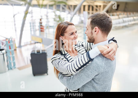 Heureux couple hugging in airport terminal lors de la reunion après un voyage Banque D'Images