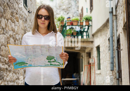 Jeune femme blonde avec une carte dans la rue. Banque D'Images