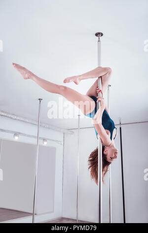 Athletic Slim pole dancer dancing sur le poteau, la tête en bas Banque D'Images