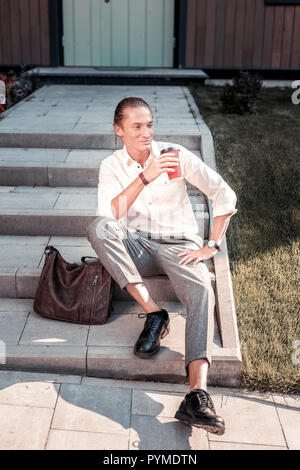 Bel homme élégant assis sur le perron en attendant que sa petite amie Banque D'Images