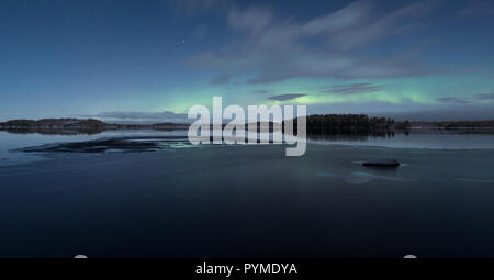 Panorama de la moitié lac glacé à la nuit d'hiver avec aurora borealis aka northern lights sur le ciel Banque D'Images