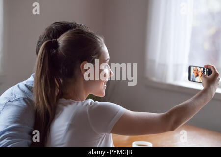 Femme tenant un téléphone avec appareil photo allumé en selfies Banque D'Images