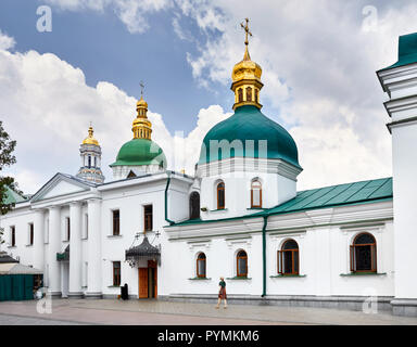 Woman in hat autour de l'Église avec dômes dorés à la Laure de Pechersk de Kiev Christian complexe. Ancienne architecture historique à Kiev, Ukraine Banque D'Images