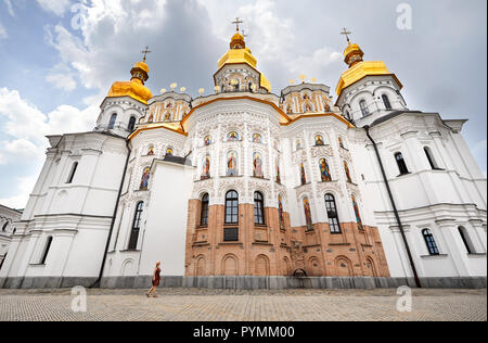 Woman in hat autour de l'Église avec dômes dorés à la Laure de Pechersk de Kiev Christian complexe. Ancienne architecture historique à Kiev, Ukraine Banque D'Images