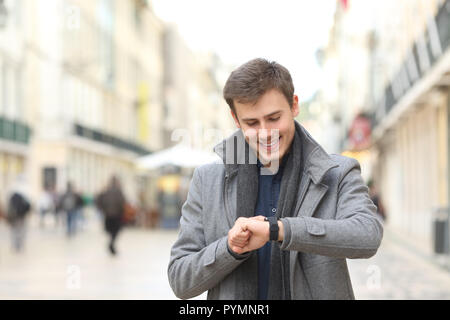 Homme heureux vérifie son smart watch dans la rue en hiver Banque D'Images