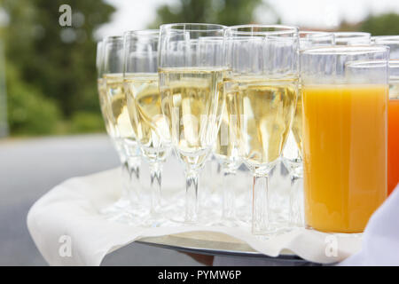 Détail d'un waiter holding un plateau de champagne et autres boissons. Des problèmes de mise au point arrière-plan vert. Banque D'Images