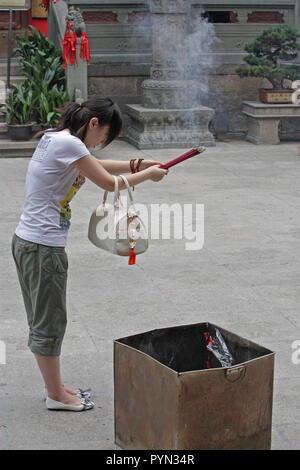 Jeune femme chinoise offrant des prières et des souhaits, temple de Jing'an, Shanghai, Chine Banque D'Images