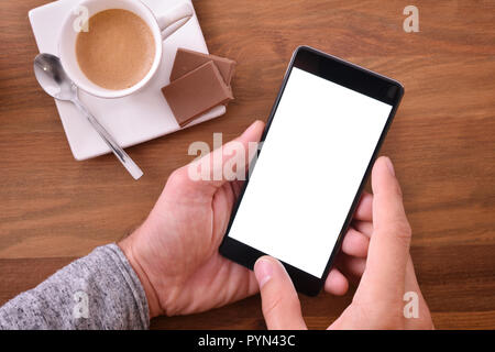 À l'aide de téléphone mobile sur table en bois dans le reste du temps avec une tasse de café et de chocolat. Vue d'en haut. Composition horizontale. Banque D'Images
