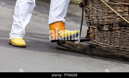 Close up d'un cavalier de la descente, traîneau traditionnel 'carrinhos de cesto', le 'Monte' dans l'île de Madère, au Portugal. Banque D'Images