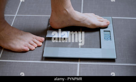 Pieds masculins sur les échelles en verre, l'alimentation, du poids corporel, Close up, l'intensification de l'homme sur les balances, side view Banque D'Images