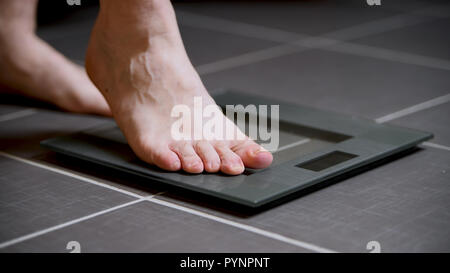 Pieds masculins sur les échelles en verre, l'alimentation, du poids corporel, Close up, marche sur l'échelle numérique, sport et vie concept Banque D'Images