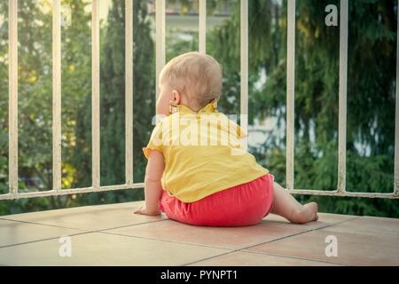 Petit bambin explore le nouveau monde à partir d'un balcon Banque D'Images