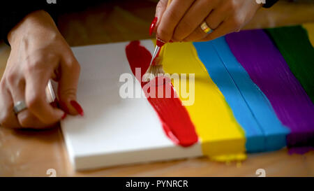 Peinture artiste féminine un arc-en-ciel avec les couleurs acryliques sur toile, hoe a fait l'art, tutoriel DIY, coloré Banque D'Images