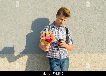 Outdoor portrait of teenage boy avec bouquet de fleurs, fond de mur gris, copiez l'espace. Banque D'Images