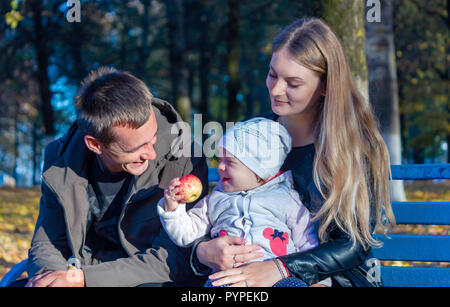 Un homme avec une femme et un enfant à l'automne est assis sur un banc Banque D'Images