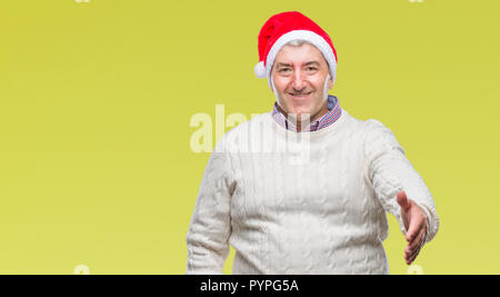 Handsome man wearing christmas hat sur fond isolé smiling friendly offrant comme message d'handshake et accueillant. Réussite de l'entreprise. Banque D'Images