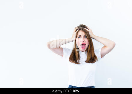 Horrible, stress, choc. Jeune femme regarde surpris émotionnelle, adhérents de l'appareil photo la tête dans les mains et ouvrant la bouche isolé sur fond blanc. Hu Banque D'Images