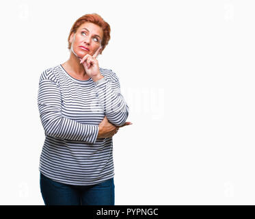 Atrractive young redhead femme de plus isolated background with hand on chin la réflexion sur la question, l'expression pensive. Smiling with me Banque D'Images