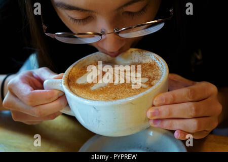 Jeune femme bénéficiant d'une belle décoration art latte. Banque D'Images