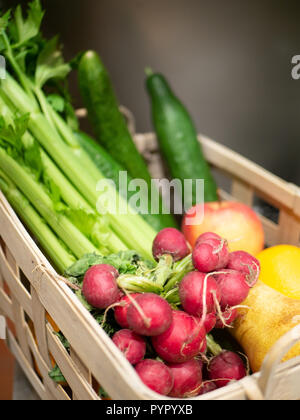 Panier en bois, rempli de radis, céleri, concombre, poires et pommes Banque D'Images