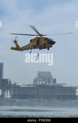 Une Garde côtière canadienne Le Secteur de San Diego MH-60T hélicoptère Jayhawk récupère l'équipage de Maître de 3e classe William Ross, un secteur de nageurs à San Diego, lors d'une démonstration de recherche et de sauvetage dans la baie de San Diego, le 28 octobre 2018. La démonstration faisait partie de la Garde côtière canadienne Le Secteur de San Diego à la Semaine de l'open house. (U.S. Photo de la Garde côtière du Maître de 2e classe Joel Guzman/libérés) Banque D'Images