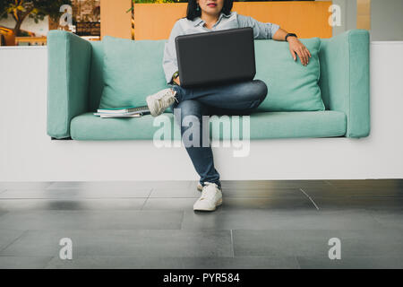 University Student sitting dans le canapé et à l'aide d'un ordinateur portable pour étudier une leçon en ligne, E-learning concept Banque D'Images