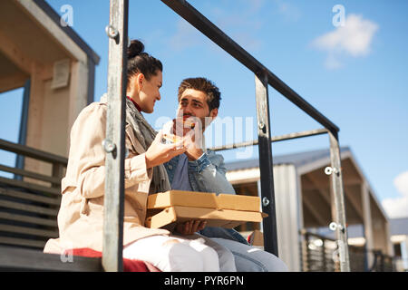 Heureux couple eating pizza on pier Banque D'Images