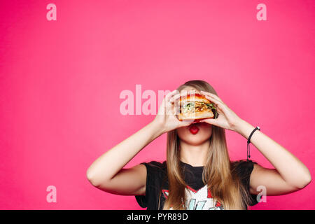 Hungry girl biting burger burger.avec poulet et salade Banque D'Images