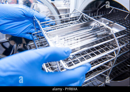 Les mains de l'assistant dentiste sortir la stérilisation des instruments médicaux d'autoclave. Focus sélectif. Banque D'Images