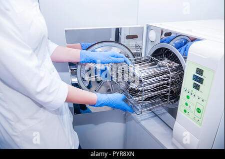 Les mains de l'assistant dentiste sortir la stérilisation des instruments médicaux d'autoclave. Focus sélectif. Banque D'Images